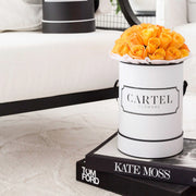 Hermes Orange Roses in a personalised monochrome white hat box with the signature Cartel Flowers branding  (the worlds first personalised flowers) You can customise and personalise the writting message on the box with anything you like for any occasion. These orange roses are styled in a lifestyle photo on a cream coloured plush floor rug and sit on top of a Kate Moss coffee table book and a Tom Ford Coffee Table book. 